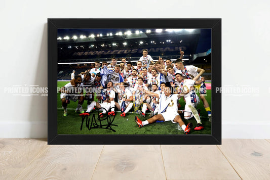 Signed (printed photo) of the 2020 Leeds United Championship squad with the league  trophy. A printed autograph taken from a genuine, certified (certificate of authenticity) autograph. A stunning signature. The print is available in a range of sizes with various framing options available.  Marcelo Bielsa is famous for sitting on his iconic blue bucket. 