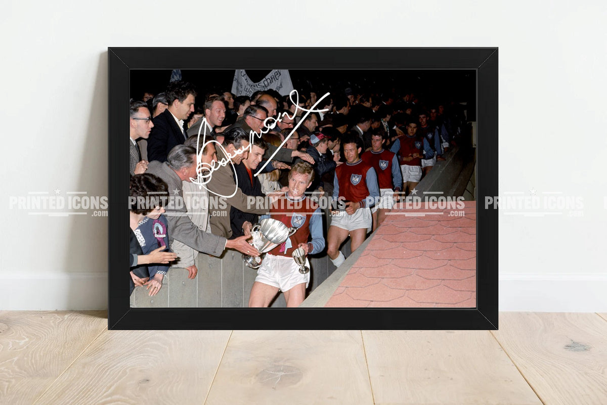 Framed Bobby Moore West Ham 1964 FA Cup photo print, featuring the Hammers captain carrying the trophy through celebrating supporters at Wembley.